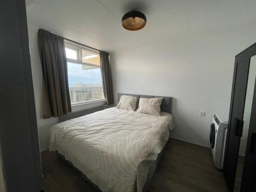a small bedroom with a bed with a window at apartment with sea view in Zandvoort