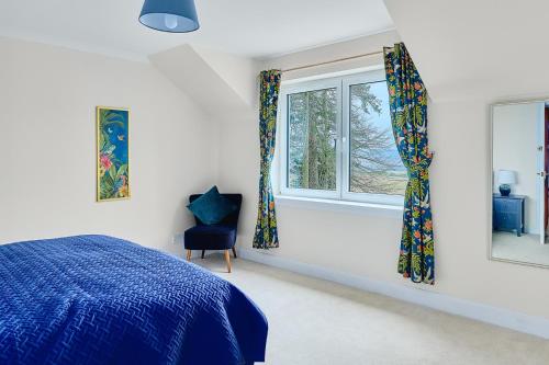 a bedroom with a blue bed and two windows at Kinkell House B&B in Cononbridge