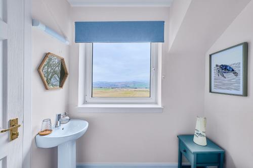 uma casa de banho branca com um lavatório e uma janela em Kinkell House B&B em Cononbridge