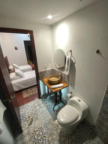 a bathroom with a toilet and a sink and a mirror at Hotel Boutique Iyarí in Palmira