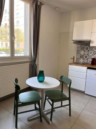 une cuisine avec une table, des chaises et un vase. dans l'établissement Le Pressensé, à Vénissieux