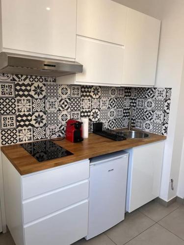 une cuisine avec des armoires blanches et un comptoir en bois dans l'établissement Le Pressensé, à Vénissieux