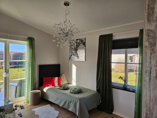 um quarto com uma cama com almofadas vermelhas e um lustre em Trevlig fritidshus på Norra Öland em Löttorp