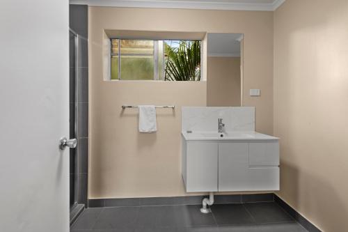 ein weißes Bad mit einem Waschbecken und einem Fenster in der Unterkunft S1 Motel in Brisbane