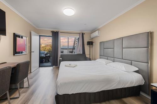 a hotel room with a large bed and a desk at S1 Motel in Brisbane