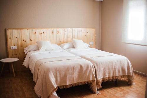 1 dormitorio con 2 camas con sábanas blancas en HOSTAL ENTREOLIVOS en Badajoz