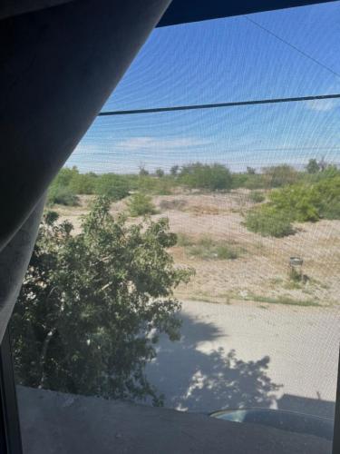 una vista del desierto con un árbol desde una ventana en Prívate room, en Torreón