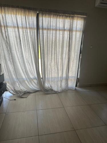 ventana con cortinas blancas y suelo de baldosa en Prívate room, en Torreón