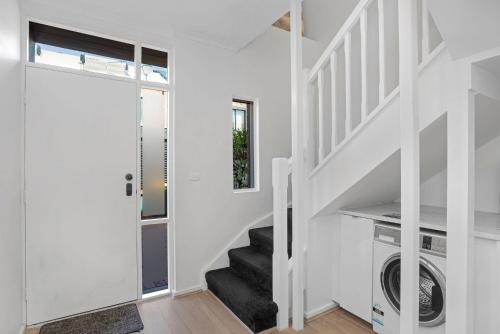 a white house with a staircase and a washer and dryer at Halifax Muse Pet Friendly Townhouse in Adelaide