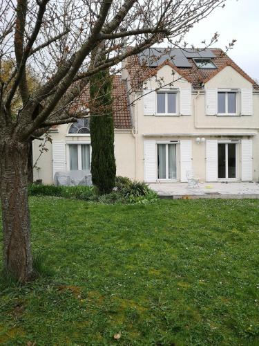 un arbre devant une maison blanche dans l'établissement Bed and breakfast jeux olympiques 2024, à Vauréal