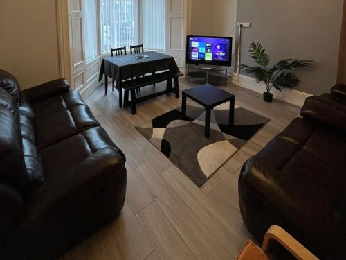 a living room with a couch and a table and a television at Arthurs Hill Newcastle, free parking fully equipped kitchen 4 bedrooms, Near city centre in Newcastle upon Tyne