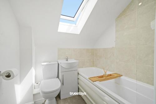 a bathroom with a toilet and a bath tub and a window at 6 Sarah House by Truestays - 2 Bedroom Apartment - FREE Wifi & Parking in Manchester