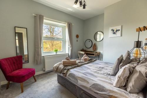 a bedroom with a large bed and a red chair at LITTLE RED HOLIDAY HOME - 2 Bed House with Free Parking within West Yorkshire, local access to the Peak District in Halifax