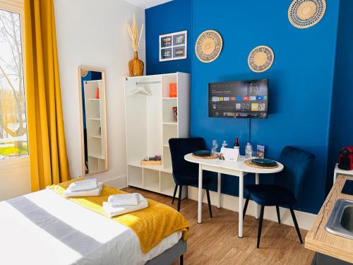 Habitación con cama, mesa y pared azul. en Le Quai Saint Laurent - BY PRIMO C0NCIERGERIE, en Orléans