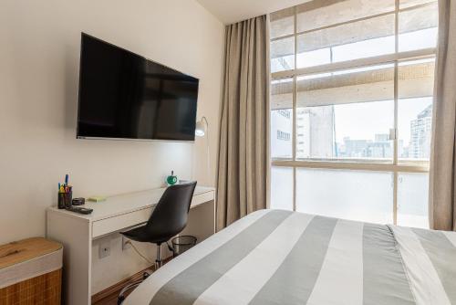 um quarto de hotel com uma cama, uma secretária e uma televisão em Apartamento no Centro - 1 quarto Edifício Copan em São Paulo