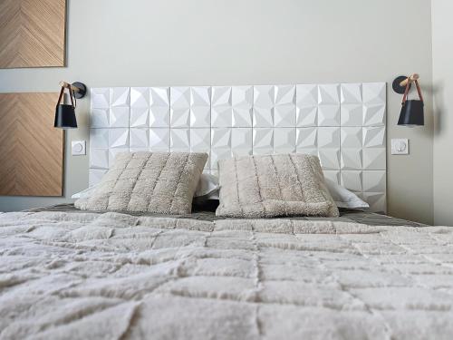 une chambre avec un lit blanc avec deux oreillers dans l'établissement le quai, à Sète