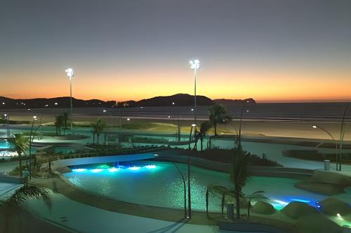 a view of a swimming pool at sunset at PRAIA DO FORTE ALTO LUXO in Cabo Frio