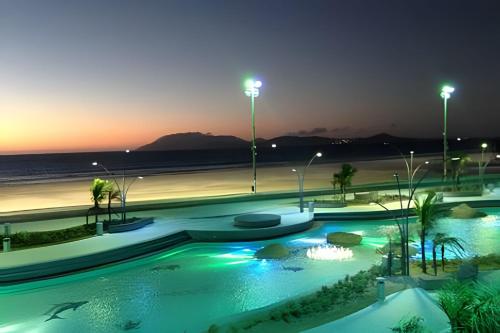 una piscina por la noche junto a una playa en PRAIA DO FORTE ALTO LUXO en Cabo Frío