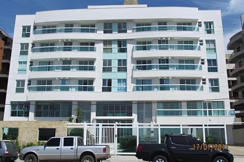 a white building with cars parked in front of it at Flat Mandai Cabo Frio in Cabo Frio