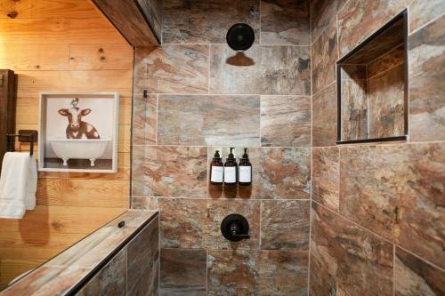 a bathroom with a shower with bottles of wine at CampQYB- Modern Lux Rustic Cabin Hot Tub FirePit Games in Runaway Bay