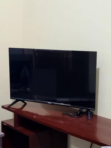 telewizor z płaskim ekranem siedzący na drewnianym stole w obiekcie Swahili home-Mbeya CBD w Mbeya