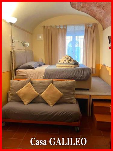 a bedroom with two beds and a bench in front of a window at Casa GALILEO- Antiche Dimore Pisane in Pisa