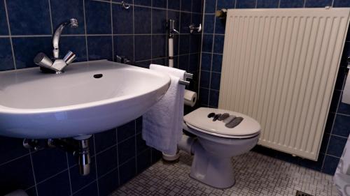 a bathroom with a white sink and a toilet at Haven - Hotel Am Stadion in Leverkusen