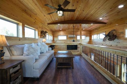 a living room with a couch and a ceiling fan at CampQYB- Modern Lux Cabin Hot Tub FirePit Sauna in Runaway Bay