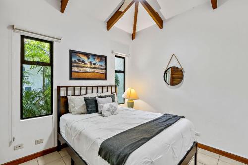 a bedroom with a bed with white sheets and windows at Peaceful Garden Villa in Sardinal