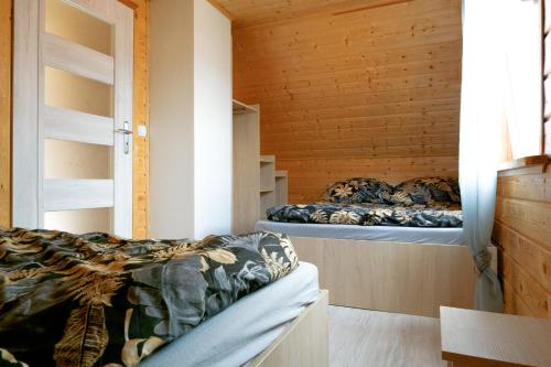 two beds in a room with wooden walls at Domki Rejs in Dębki