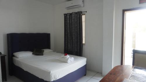 a bedroom with a bed with a black headboard and a window at Old Relaxing in Belize City