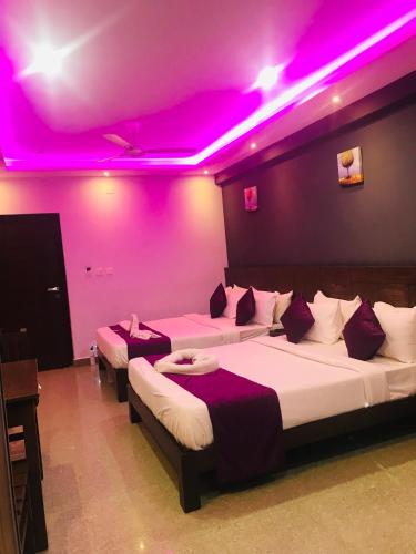two beds in a room with pink lighting at Coorg ASHOK PALACE in Madikeri
