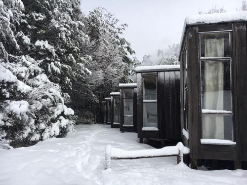 a group of huts are covered in snow at La Baita Conguillio in Conguillío