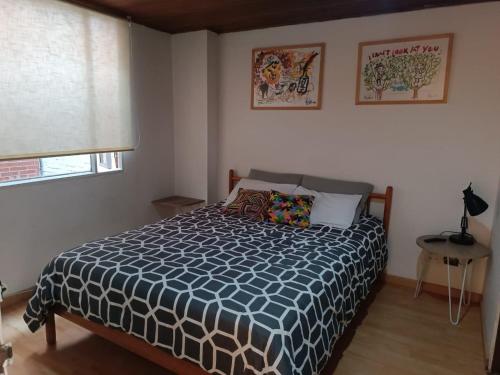 Schlafzimmer mit einem Bett mit einer blauen und weißen Bettdecke in der Unterkunft Apartamento con balcón Javeriana in Bogotá