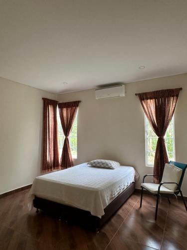 um quarto com uma cama, uma cadeira e 2 janelas em Verde del Limonar Casa de Campo em Girardot