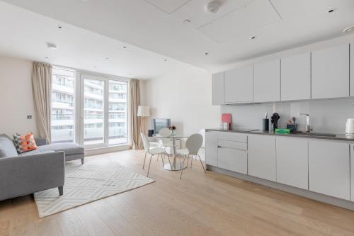 a kitchen with white cabinets and a living room at Luxury 2 bed 2 bath close to Chelsea in London