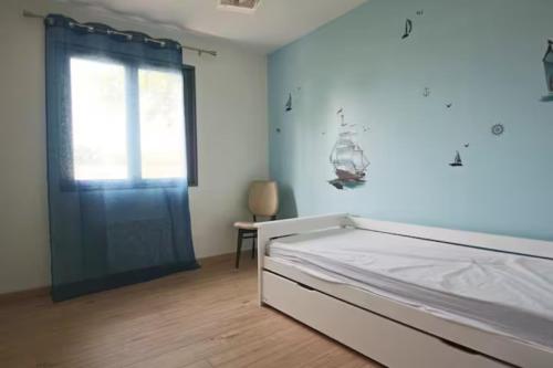 une chambre avec un lit et un mur bleu dans l'établissement Maison landaise contemporaine, à Andernos-les-Bains