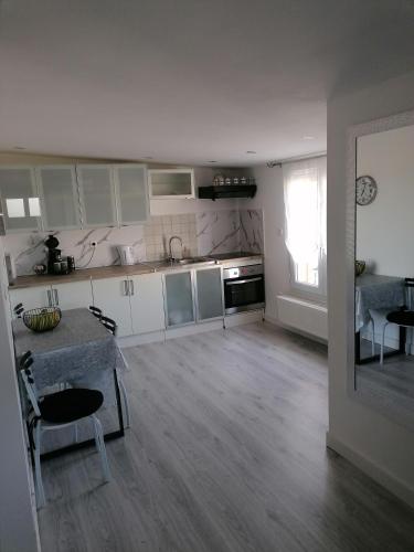 una cocina con armarios blancos y una mesa en una habitación en Appartement moderne en Rouvroy