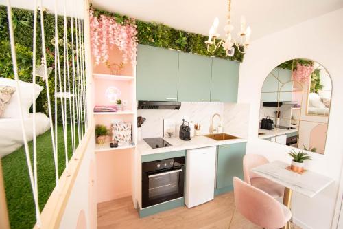 uma cozinha com armários azuis e uma parede verde em Studio les 2 fées - Jacuzzi et Décoration Enchantée em Montfort-sur-Meu
