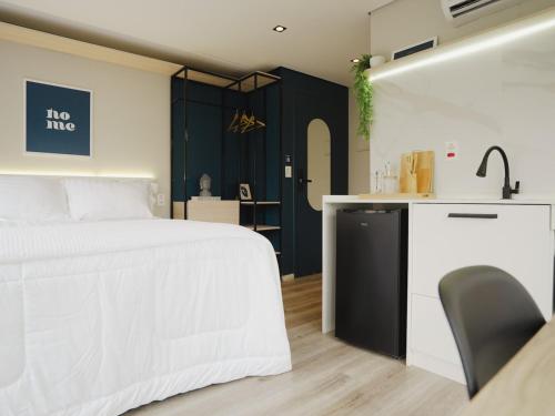 a bedroom with a white bed and a kitchen at Apê Paulista Bela Cintra in Sao Paulo