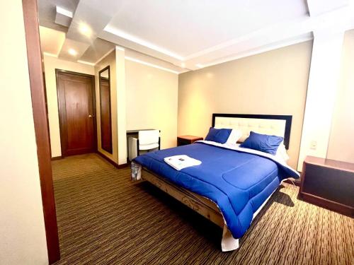 Habitación de hotel con cama con sábanas azules en 1420 Lujosa Habitación - Hotel Akros, en Quito