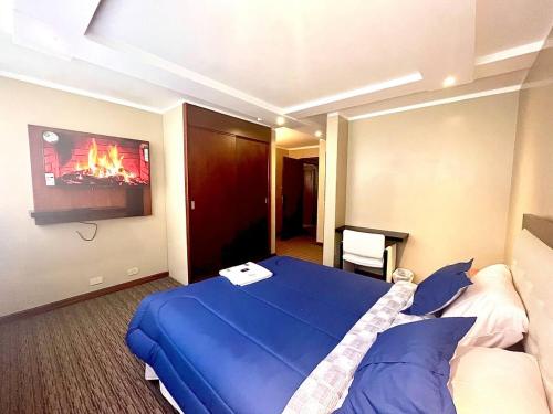 a hotel room with a blue bed and a tv at Lujosa Habitación - Hotel Akros in Quito