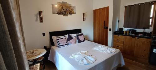 a bedroom with a bed with white sheets and pillows at Mountain House Hospedagem in Monte Verde