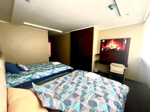 a bedroom with a bed and a tv on the wall at Lujosa Habitación - Hotel Akros in Quito