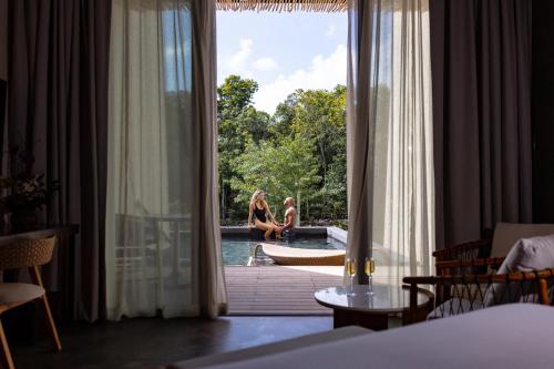 two people sitting on the edge of a pool in a hotel room at Secrets Tulum Resort & Beach Club - Adults Only - All Inclusive in Tulum