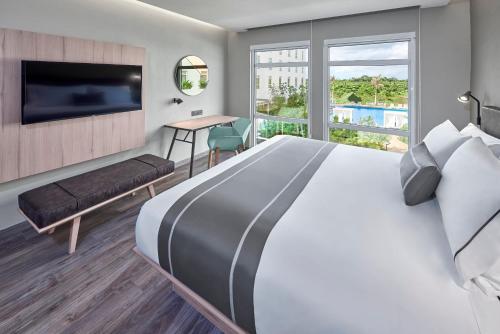 um quarto de hotel com uma cama grande e uma televisão em City Express Plus by Marriott Cancun Aeropuerto Riviera em Cancún