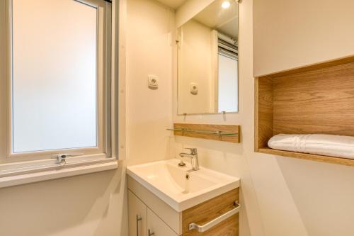 baño con lavabo, ventana y espejo en Mobilhome 530 - 8 places, en Lattes