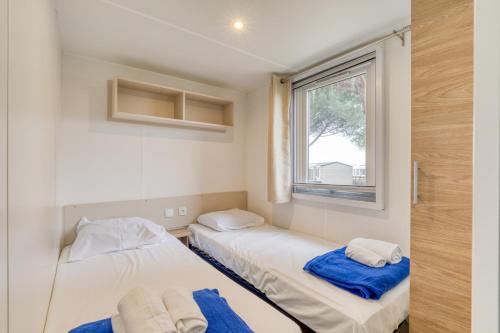 2 camas en una habitación con ventana en Mobilhome 530 - 8 places, en Lattes