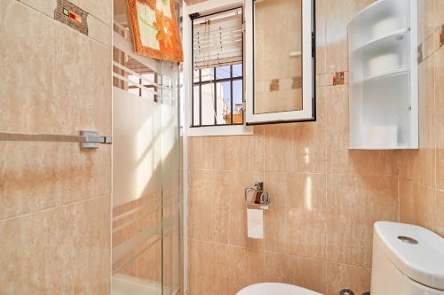 a bathroom with a toilet and a glass shower at Casa Ian in Frigiliana
