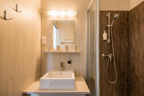 La salle de bains est pourvue d'un lavabo et d'une douche. dans l'établissement FairSleep Motel Einstein Erding, à Erding